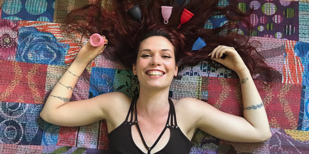 girl laying on a bed with a bunch of menstrual cups