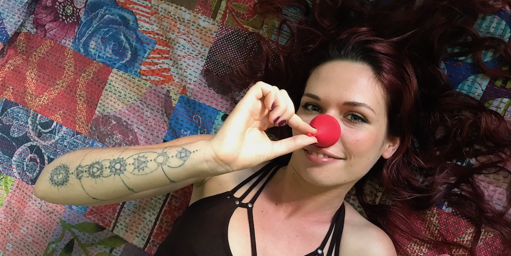girl holding a red menstrual cup on her nose
